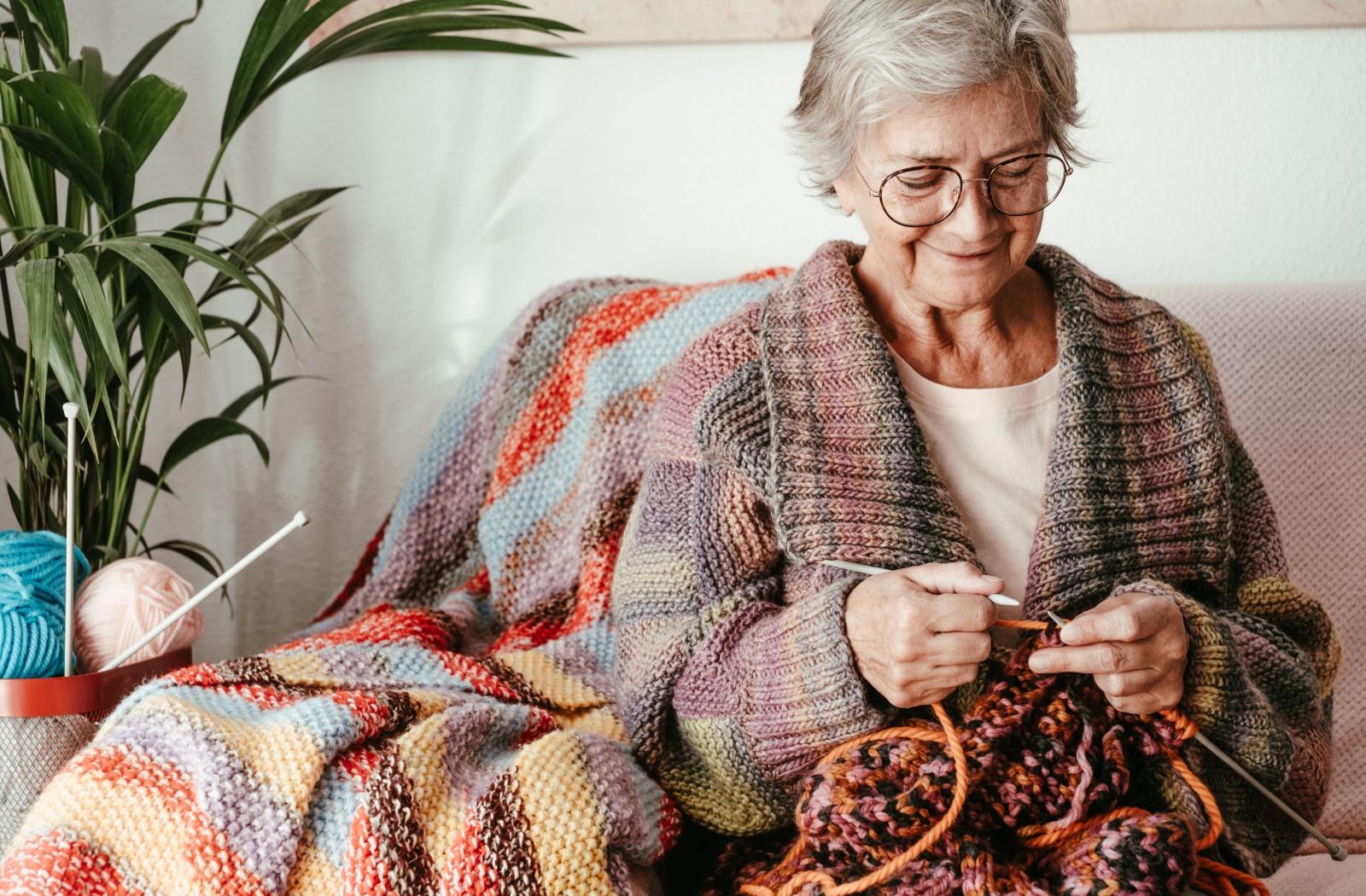 A smiling senior relaxes and enjoys an afternoon knitting.