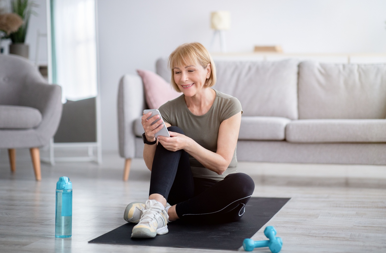A senior uses their smartphone to view yoga videos taught by professionals to follow along at home to stay physically fit
