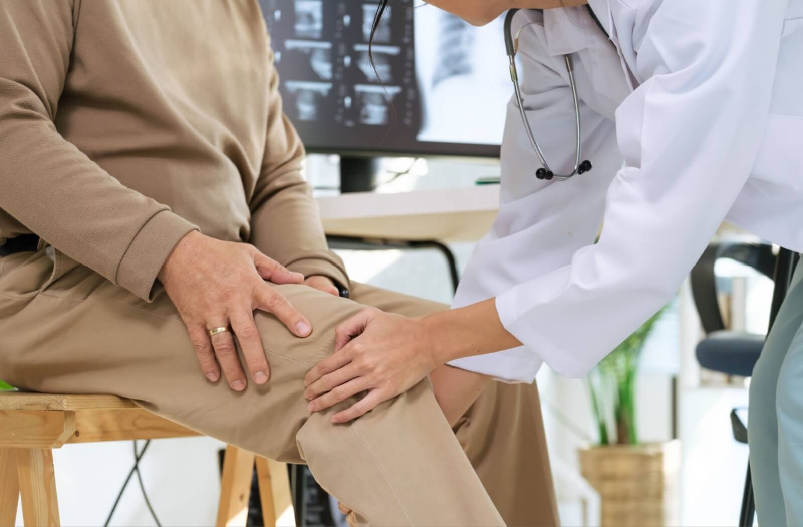 A caregiver gently touches an older adult's knee during a quick checkup to find what's causing their knee discomfort