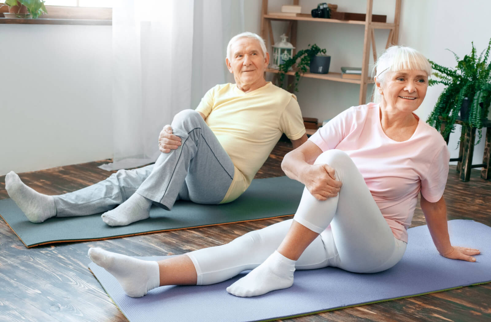 A senior couple in their living room, doing yoga together.