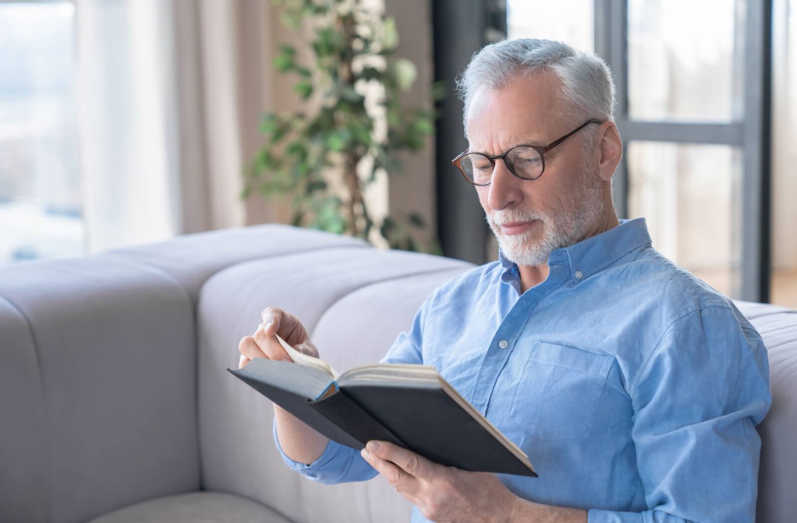 A content senior reads a book in their home within an independent senior living community.