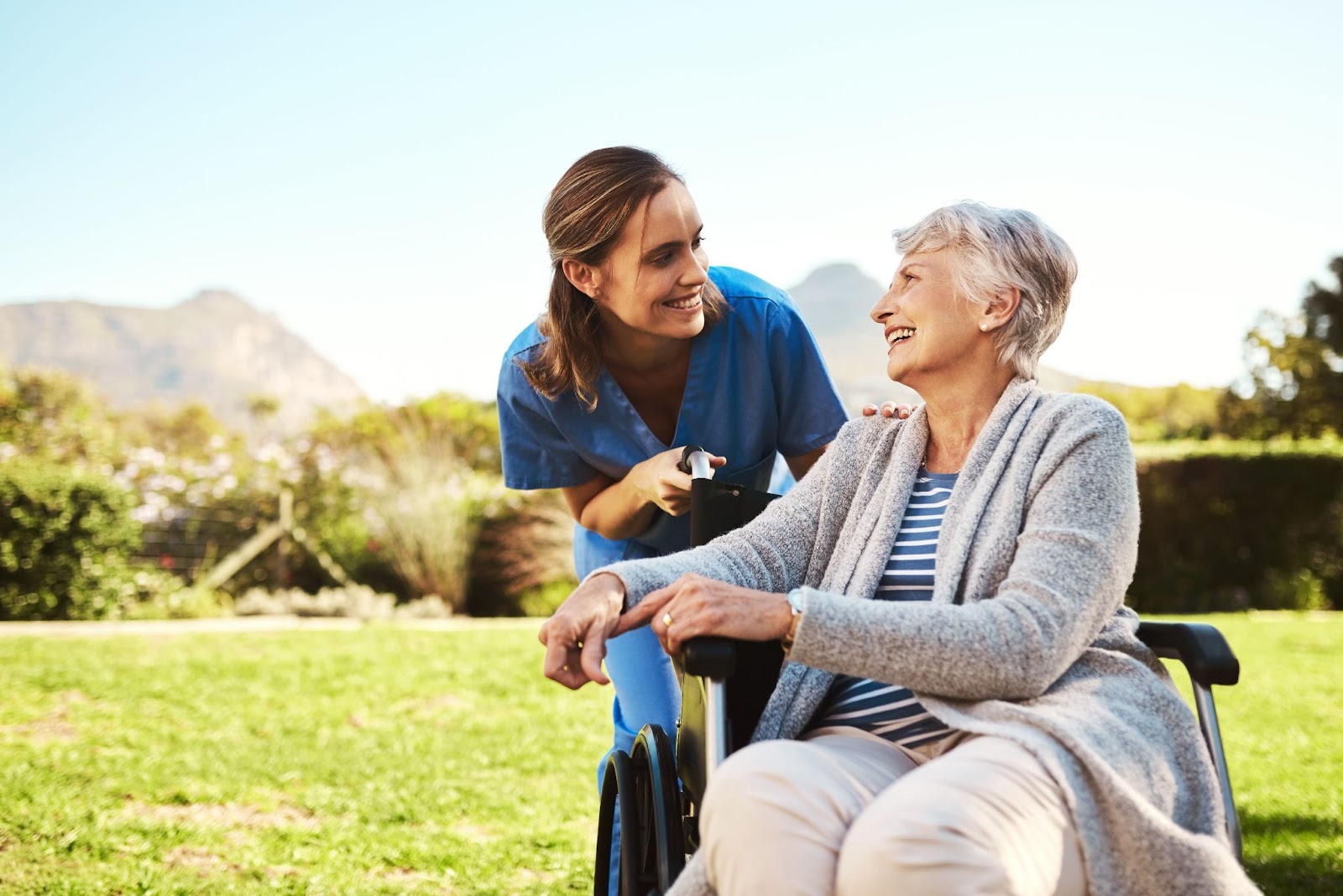 A smiling senior enjoys some time outside with her caregiver.